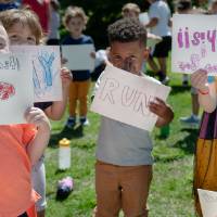 Children from the GVSU's Enrichment Center hold up signs to cheer on the racers.